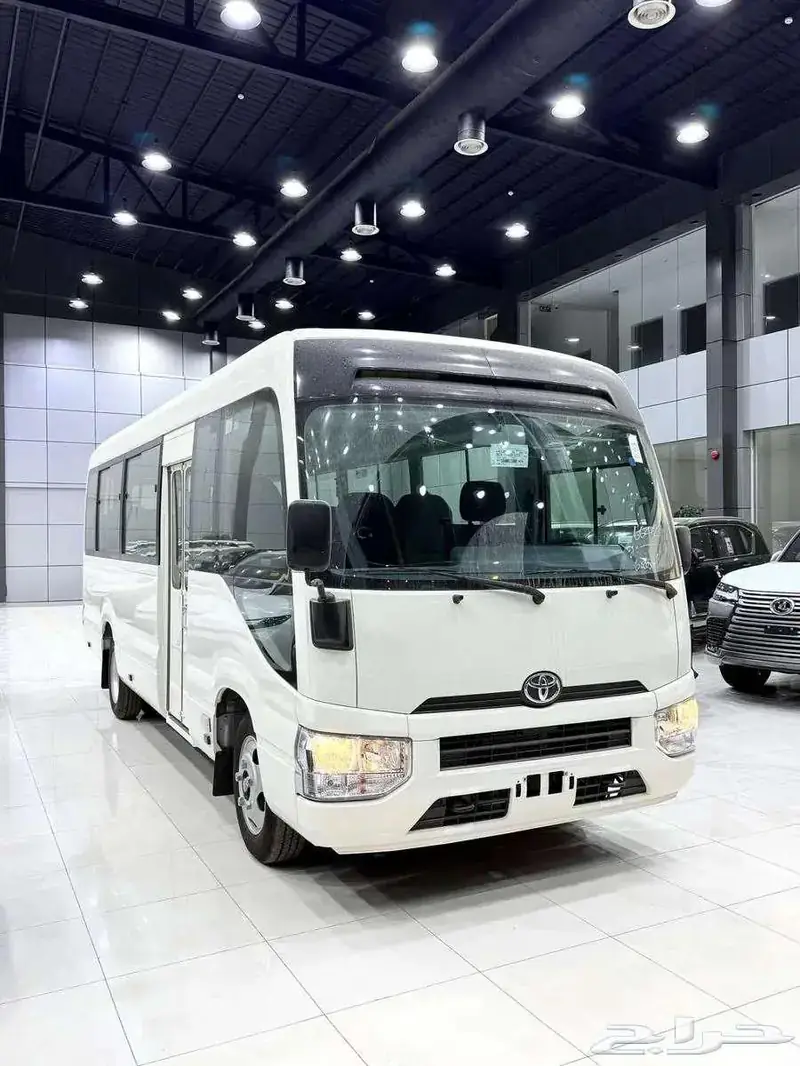 White Toyota Coaster 5C Saloon bus available for group travel in Pakistan