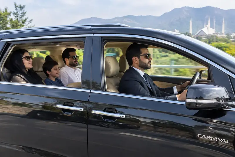 A professional driver opening the door of a sedan in Islamabad